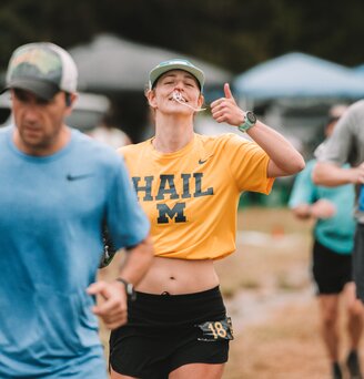 A woman running with a thumbs up.